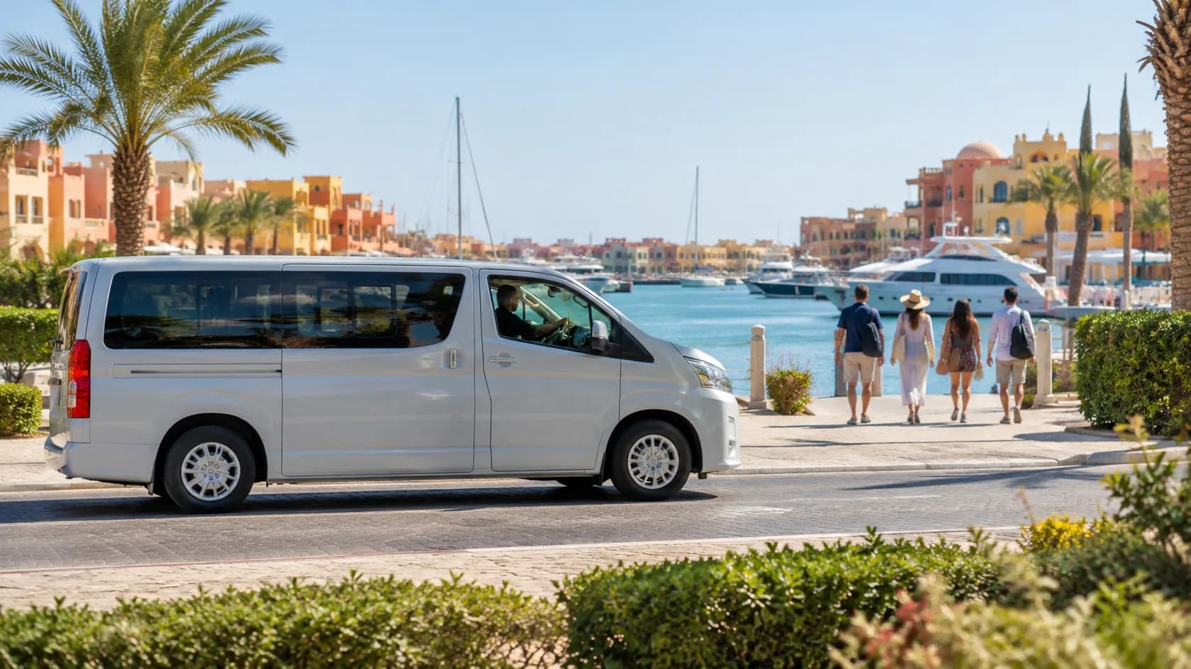 Silver passenger van parked beside a sunny marina as four visitors walk toward yachts, colorful buildings and palm trees